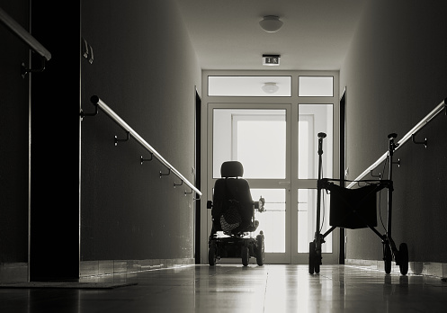 empty wheelchairs in a dark hallway of a nursing home.